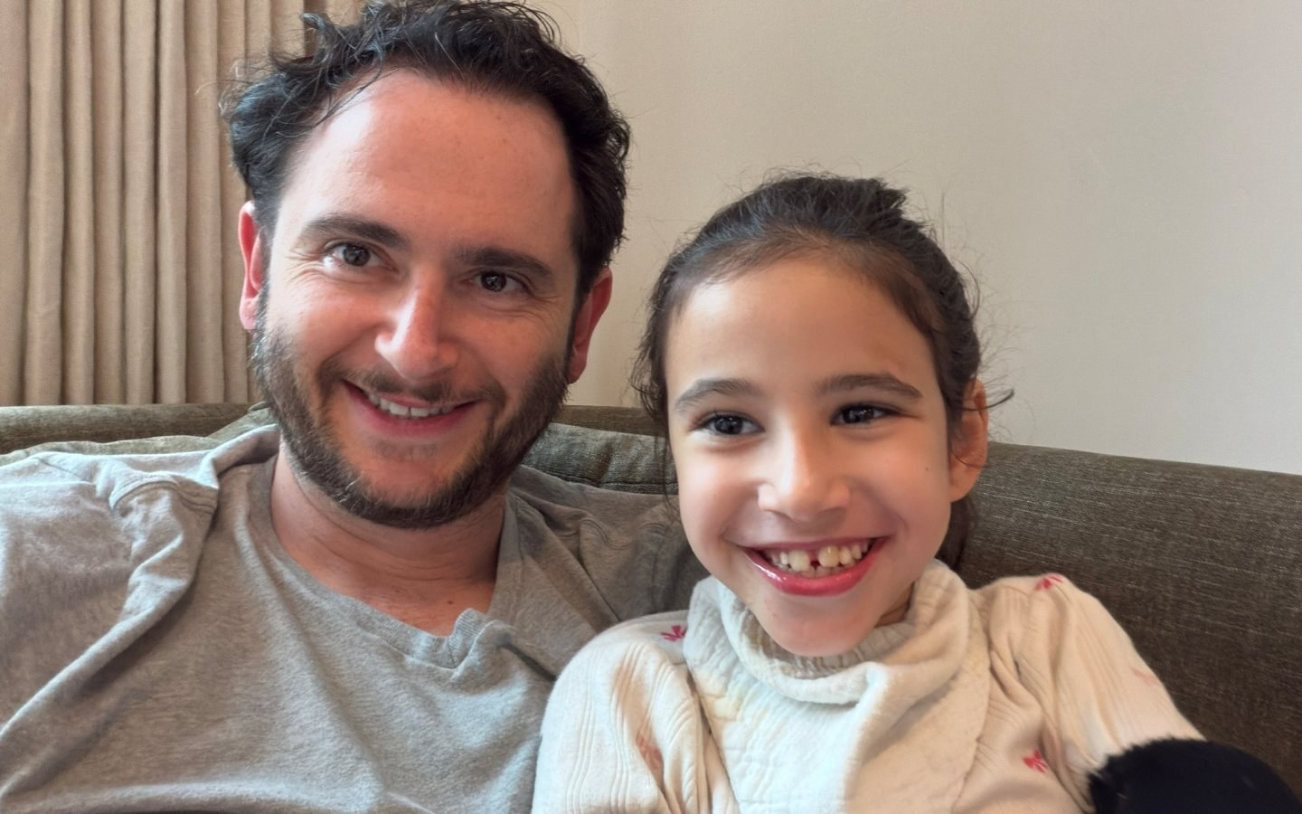 Ellie and her dad on the couch, both grinning